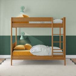 Wooden bunk bed with ladder in kids' bedroom, green two-tone wall, mint wall sconces, striped sheets and mustard-yellow bedding