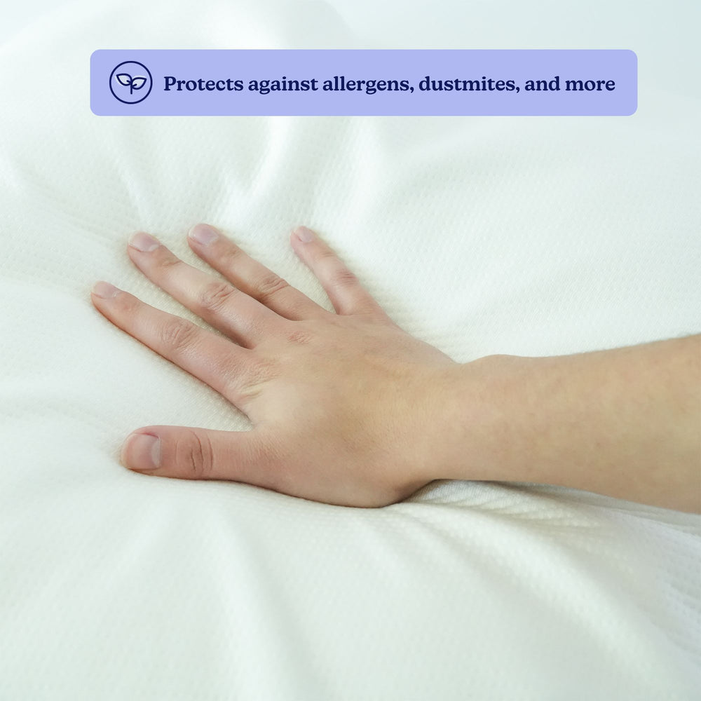 Hand pressing down on a white mattress protector that provides protection against allergens and dust mites.