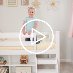 Toddler smiling on a cozy loft bed in a nursery with shelves and plush decor.