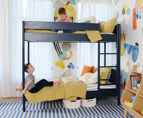 Children playing on a bunk bed in a colorful room with abstract wall art.