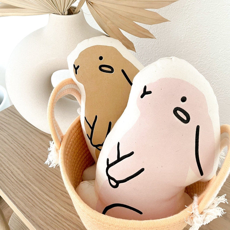 Cute animal-shaped plush pillows in a beige basket next to modern vase decor.