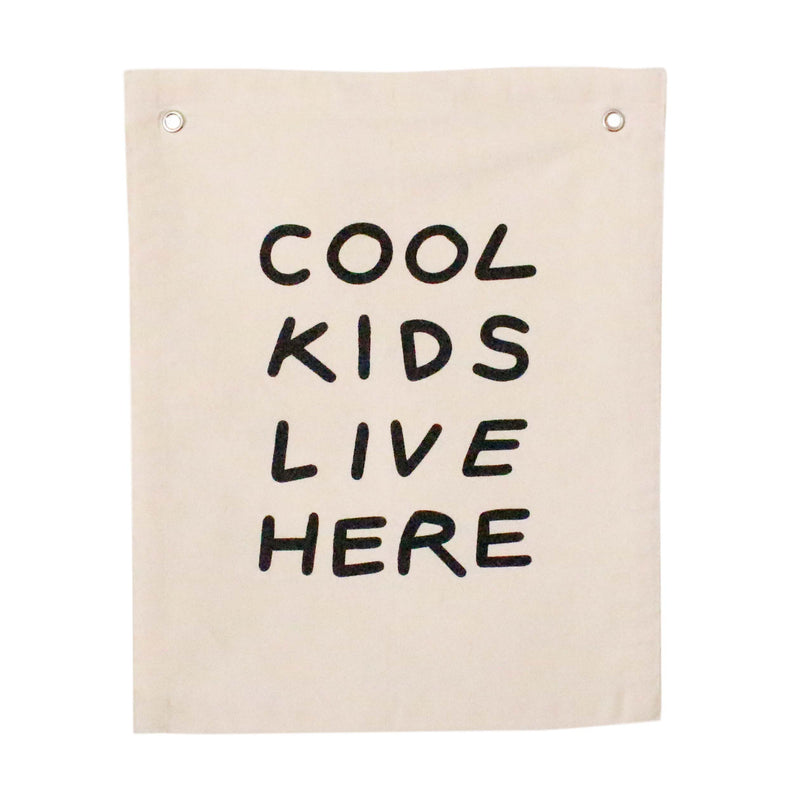 Decorative beige wall hanging with the phrase 'Cool Kids Live Here' in bold black text, ideal for children's room decor.