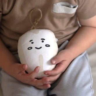 Child holding cute plush toy with smiling face, cozy home setting.