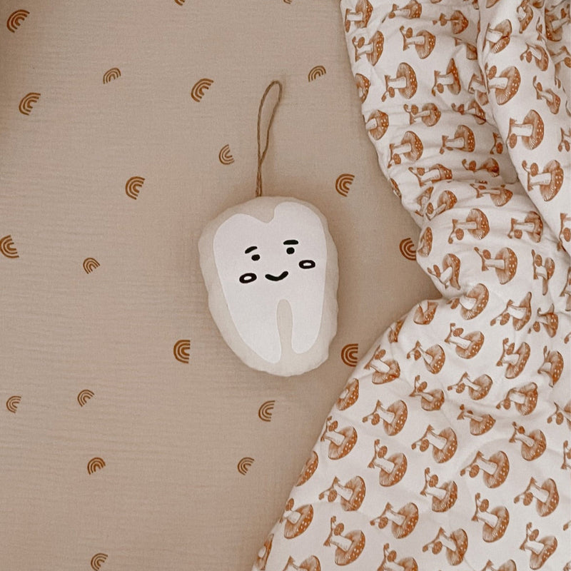 Cute tooth-themed nursery decor with natural patterns on bedding.