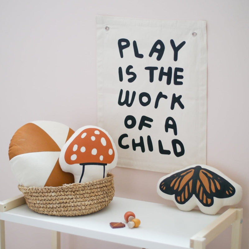Wall decor with "Play is the Work of a Child" quote and playful cushions in a child-friendly room.