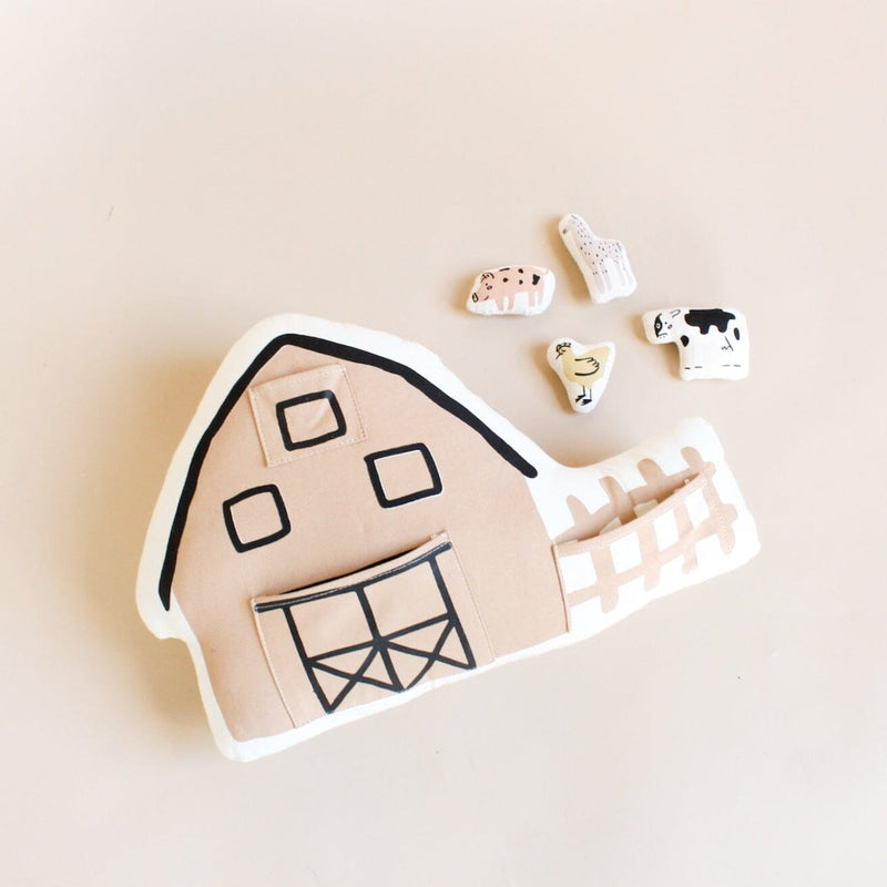 Soft toy set featuring a fabric barn with plush farm animals including a cow, pig, chicken, and sheep on a beige background.