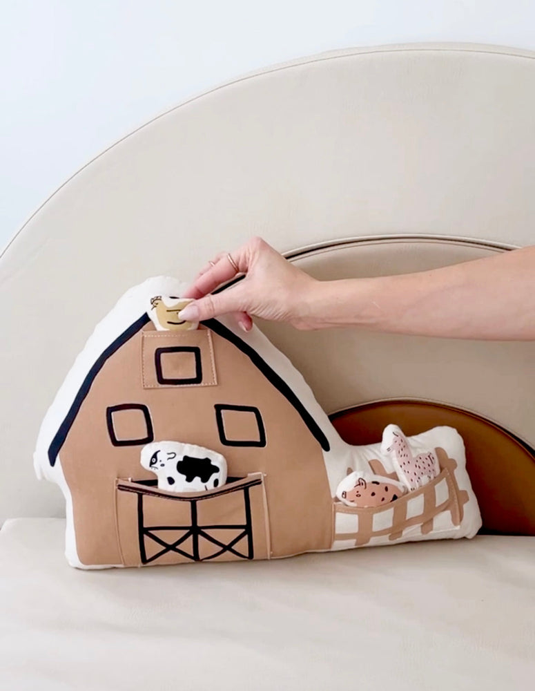 Soft toy barn with animal figures for child play and learning.