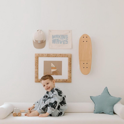 Child sitting on a white couch in a playful bedroom with a skateboard and wall art.