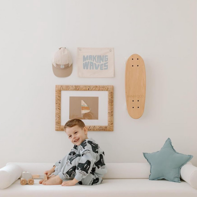 Child sitting on a white couch in a playful bedroom with a skateboard and wall art.