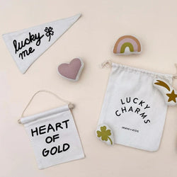 Lucky charms and accessories including a pouch, heart shape, rainbow, and banners with positive messages on a beige background.