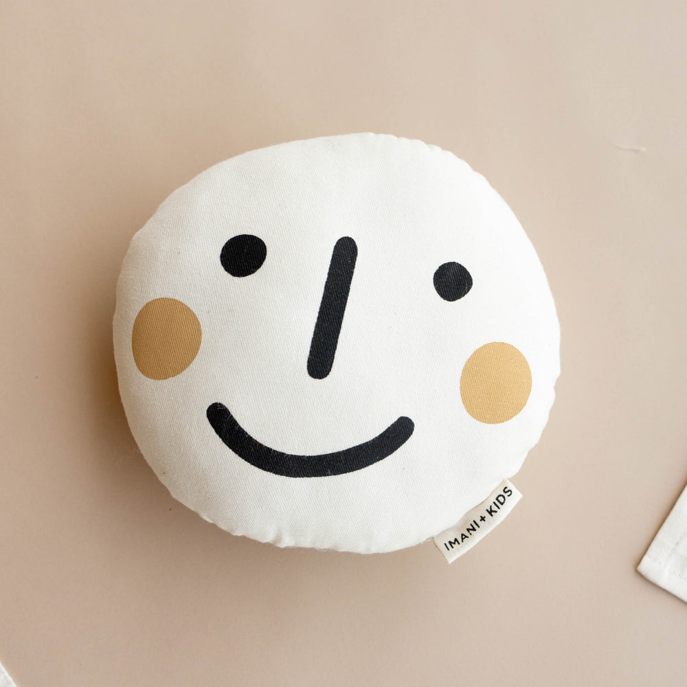 Smiley face cushion pillow for kids with beige background.
