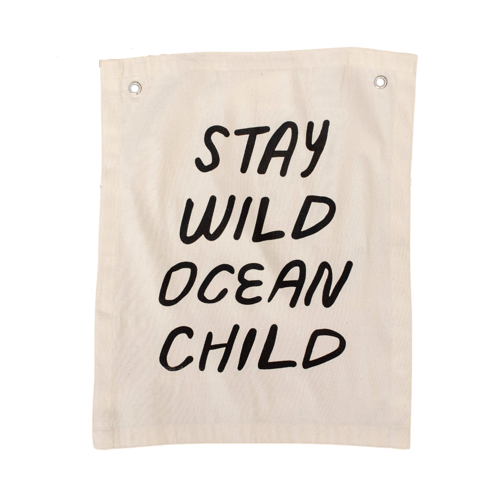Canvas wall hanging with the text "Stay Wild Ocean Child" in bold black letters.
