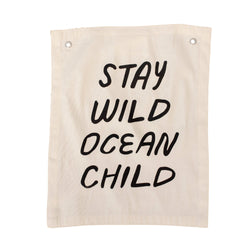 Canvas wall hanging with the text "Stay Wild Ocean Child" in bold black letters.