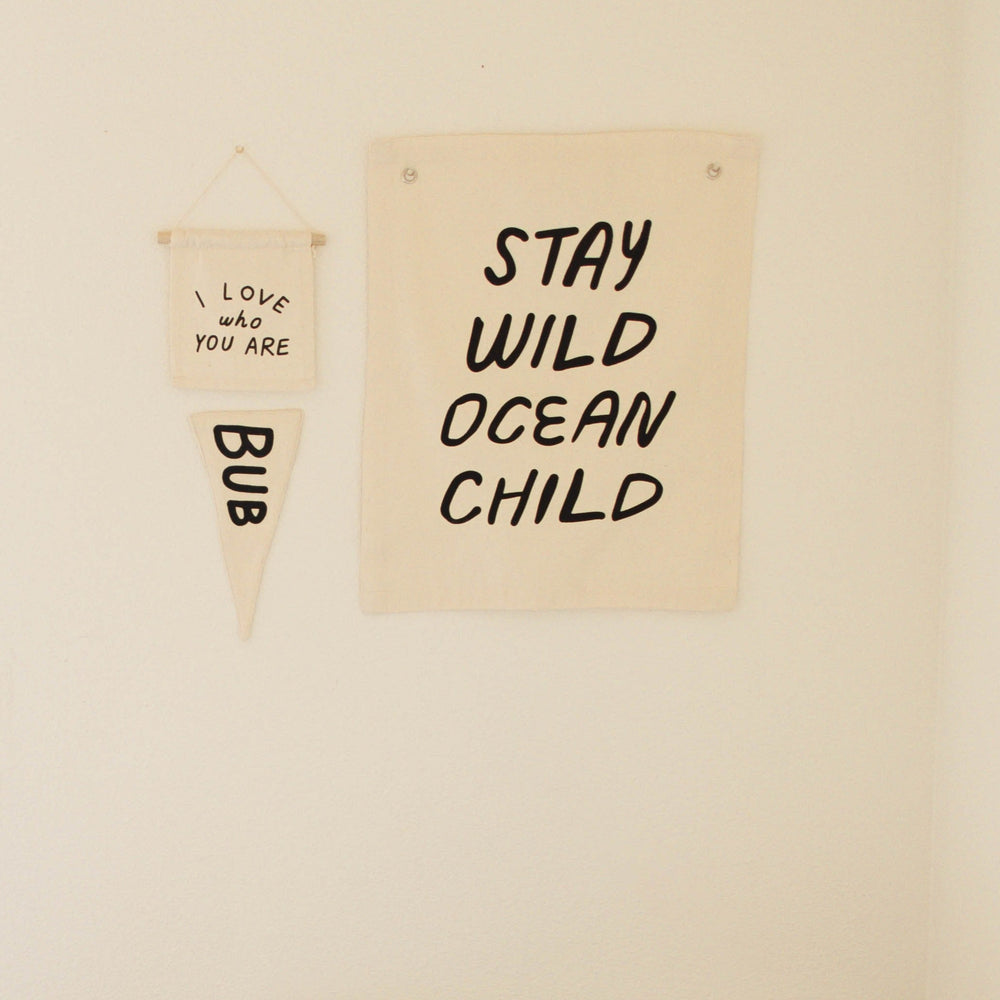 Decorative wall hangings with motivational quotes, including "Stay Wild Ocean Child" in modern minimalist style.