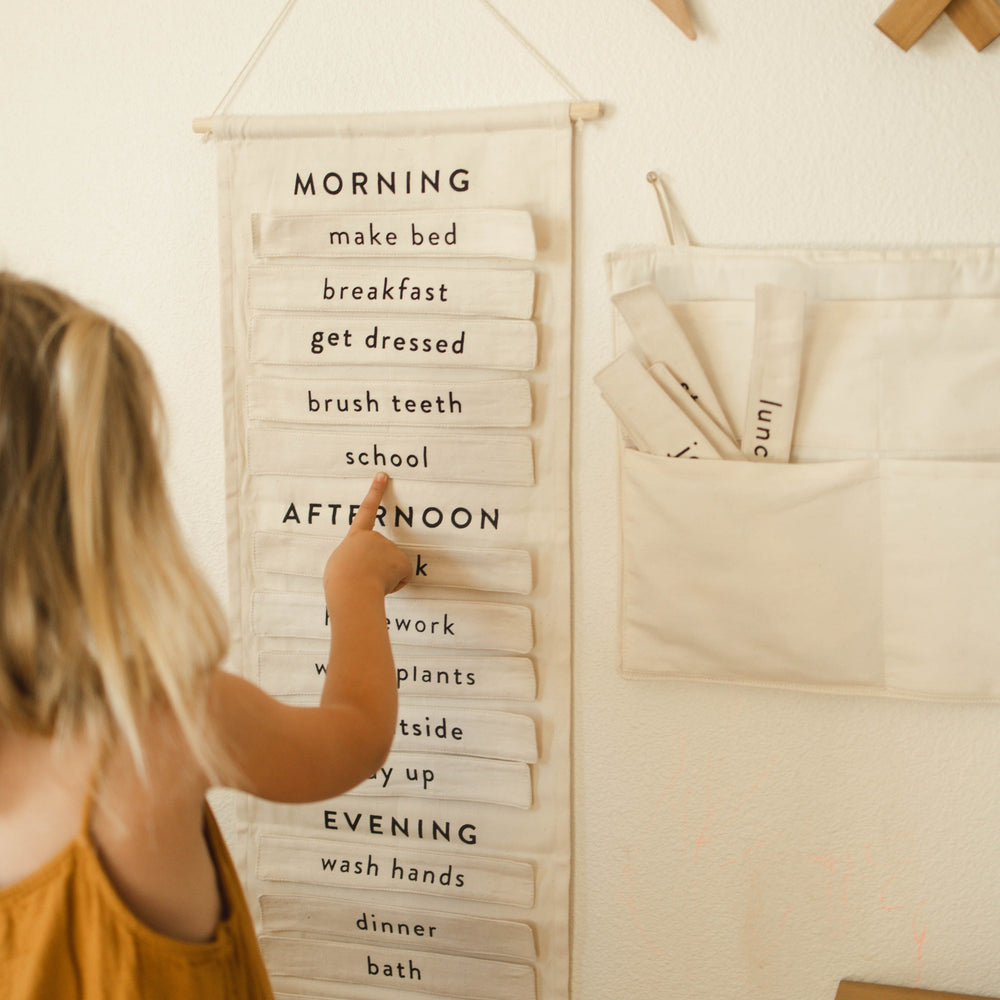 Child interacting with a daily routine chart featuring morning, afternoon, and evening tasks, promoting organization and time management skills for kids.