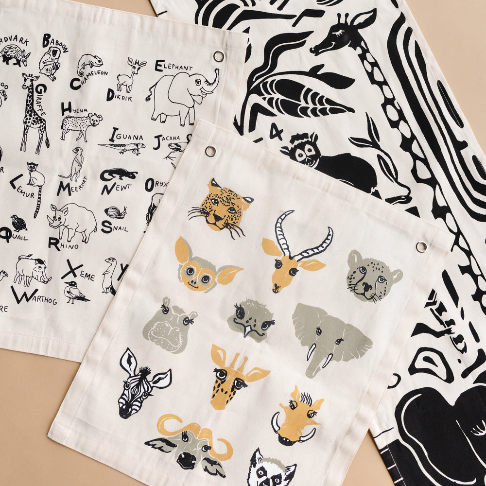 Illustrated alphabet print tea towels featuring various animal designs in black and white, perfect for kitchen decor and learning.