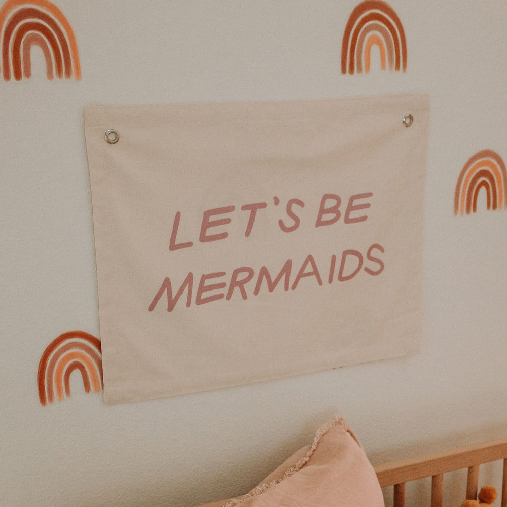 Wall decor with "Let's Be Mermaids" sign and rainbow design for playful home interiors.