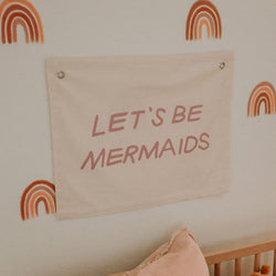 Wall decor with "Let's Be Mermaids" sign and rainbow design for playful home interiors.