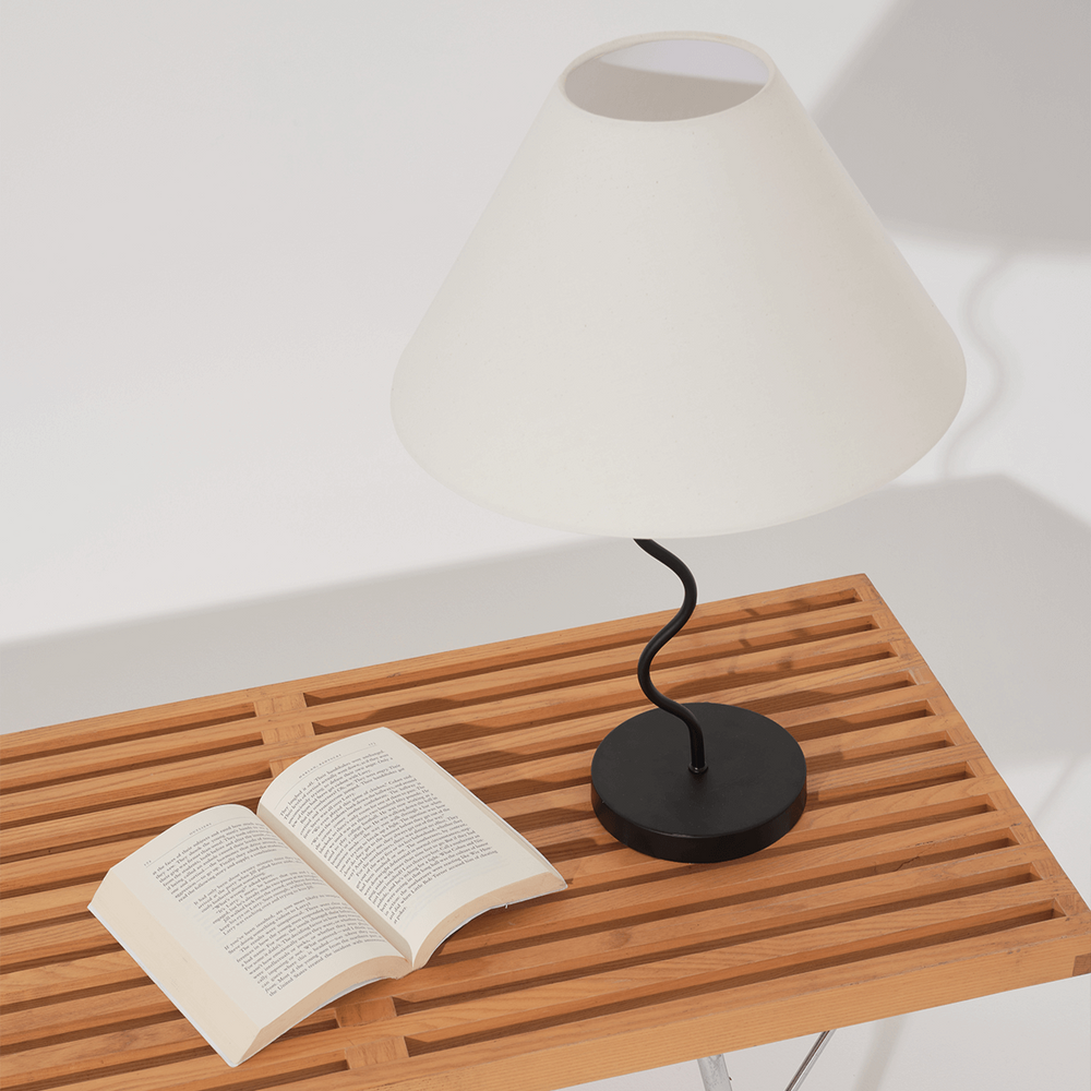 Modern black and white table lamp on wooden table with an open book.