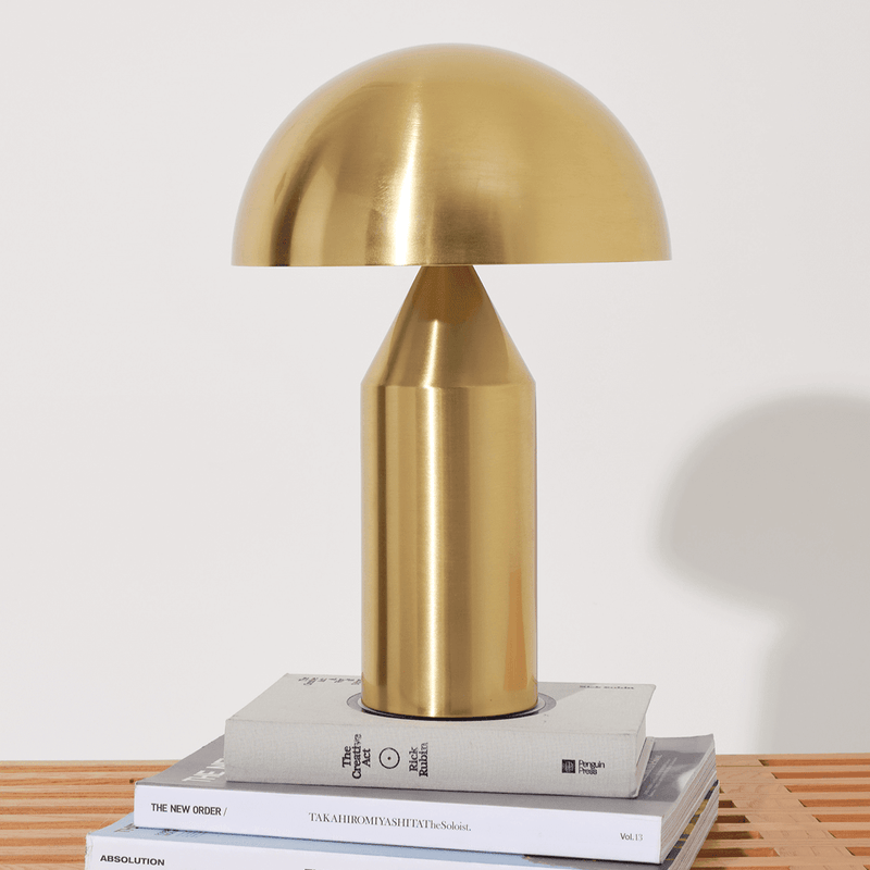 Elegant modern brass table lamp on stacked books for stylish home decor.