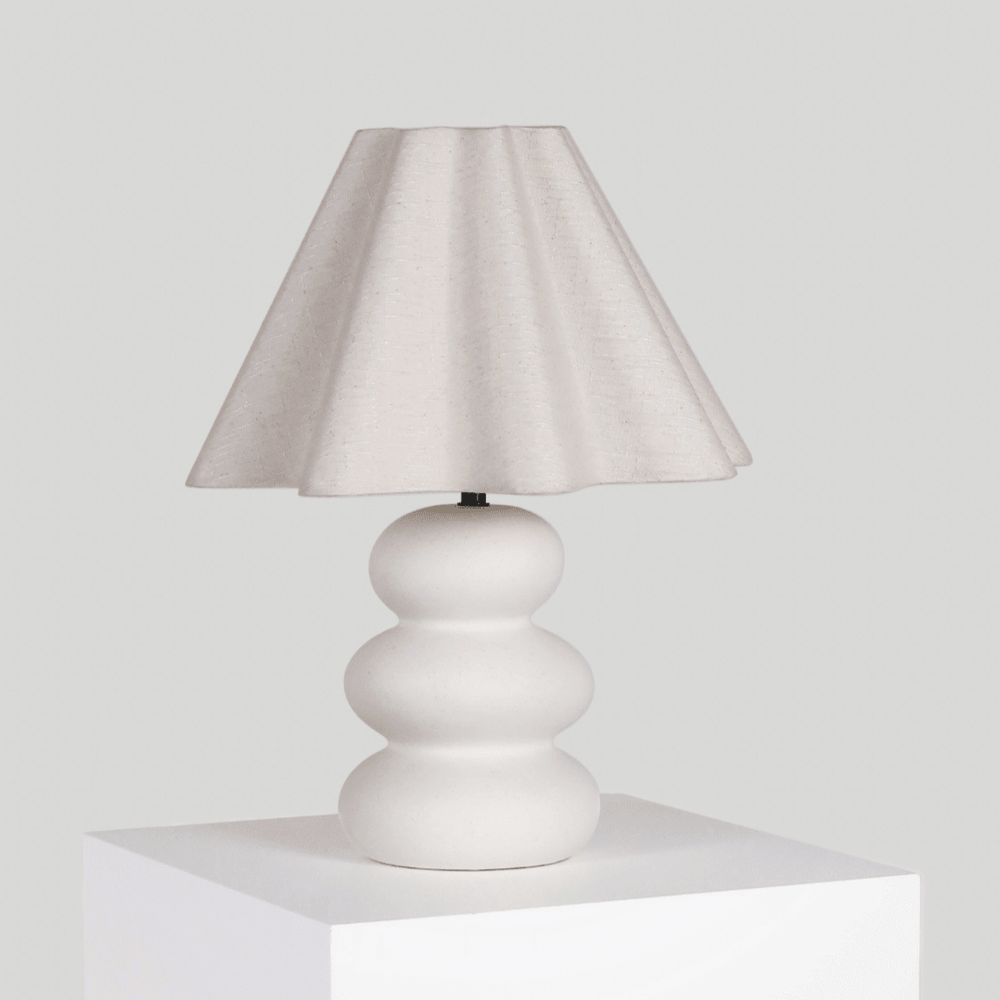 Contemporary white table lamp with sculpted base and fabric lampshade.