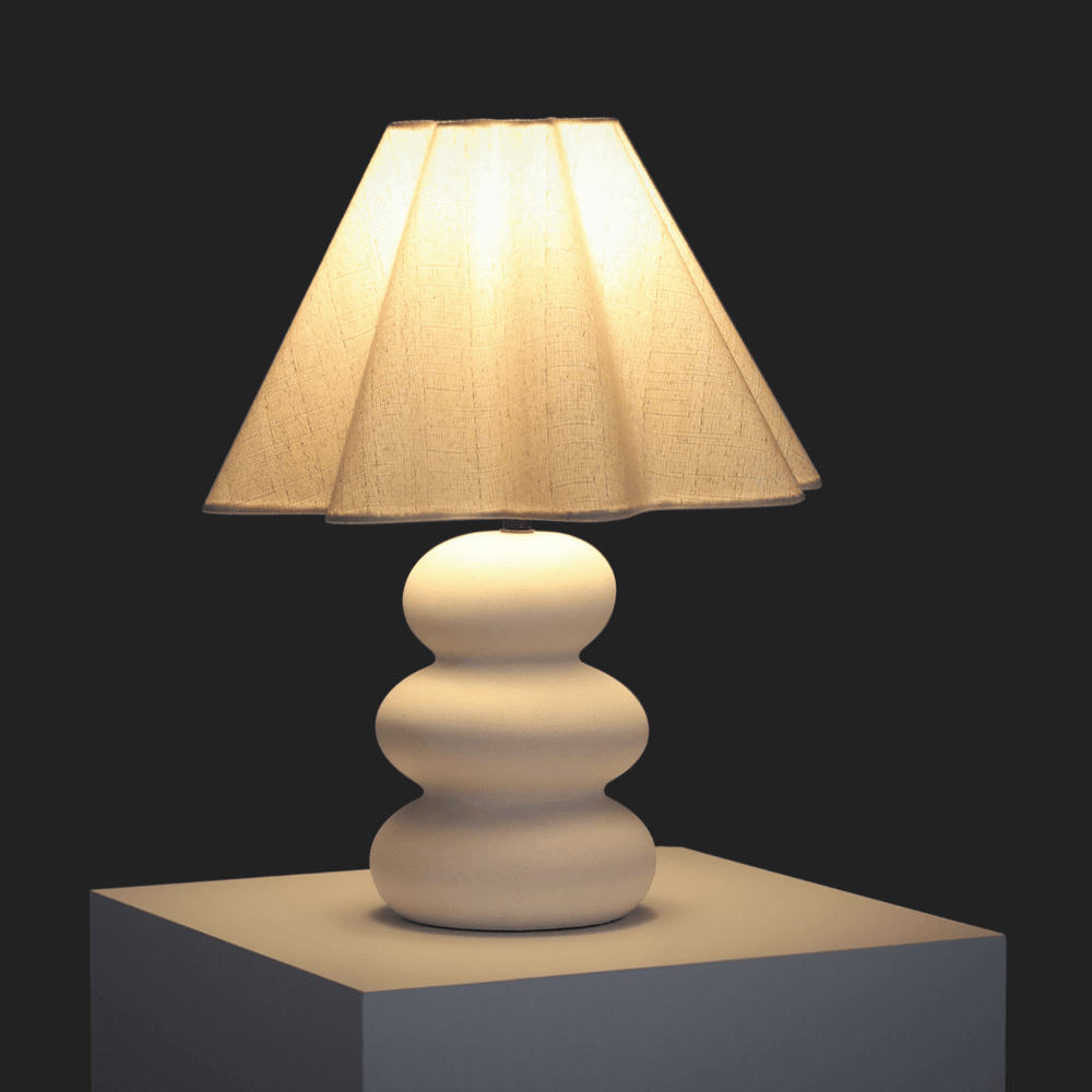 Contemporary table lamp with a beige fabric shade and a modern sculptural base.