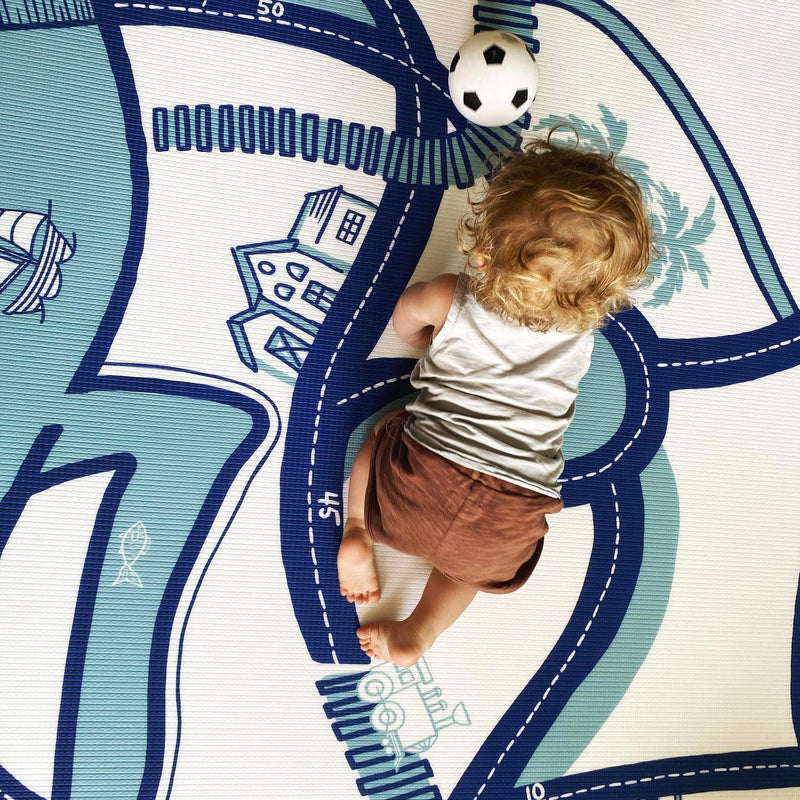 Toddler playing on a colorful playmat with a soccer ball, enhancing motor skills development.