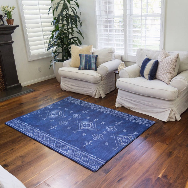 Cozy living room with white sofas, wooden floor, and blue patterned area rug.