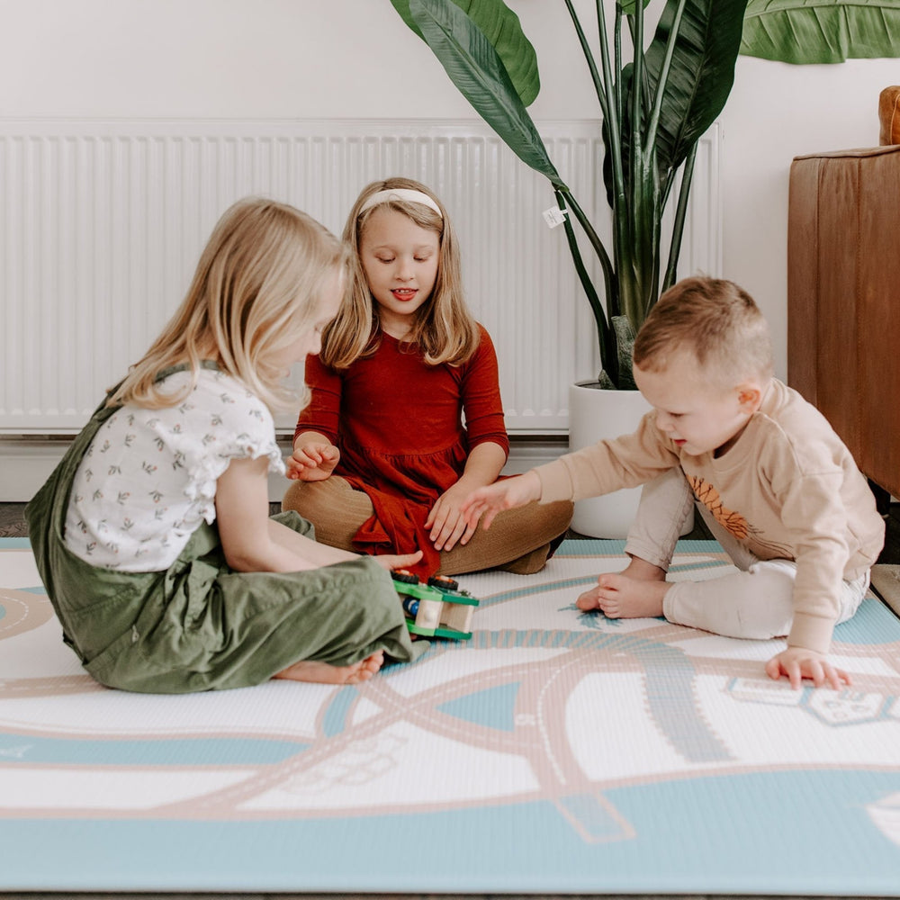 Children playing with toys on a colorful playmat in a cozy living room setting.