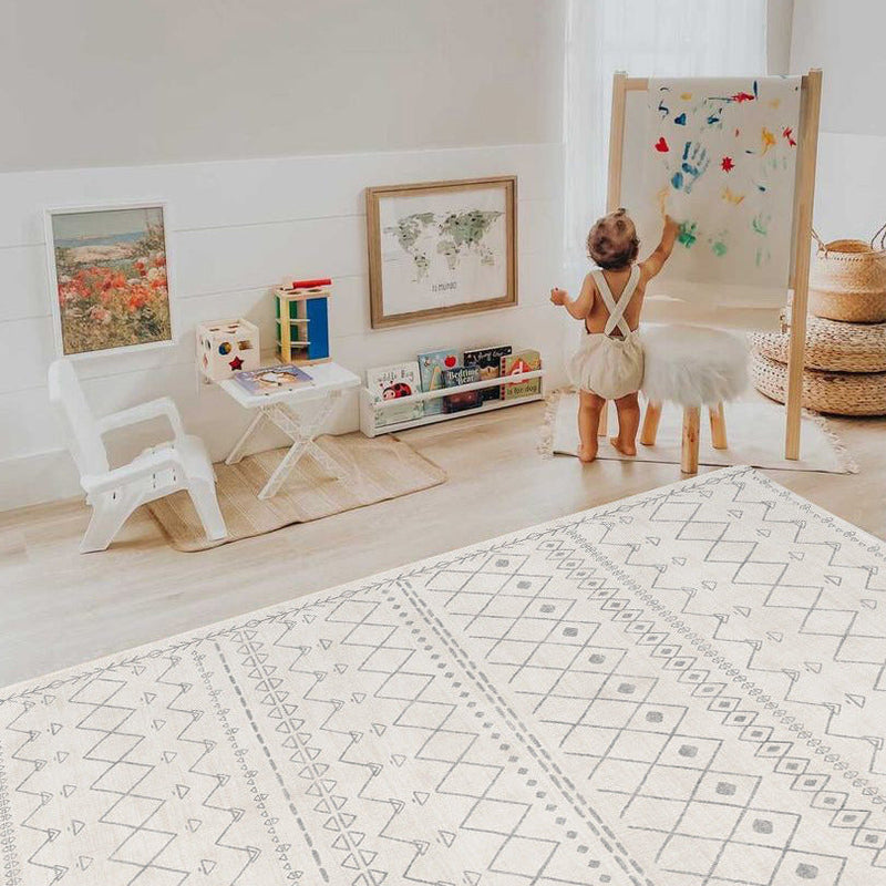 Toddler painting on easel in a bright, playful nursery with educational toys and world map artwork.