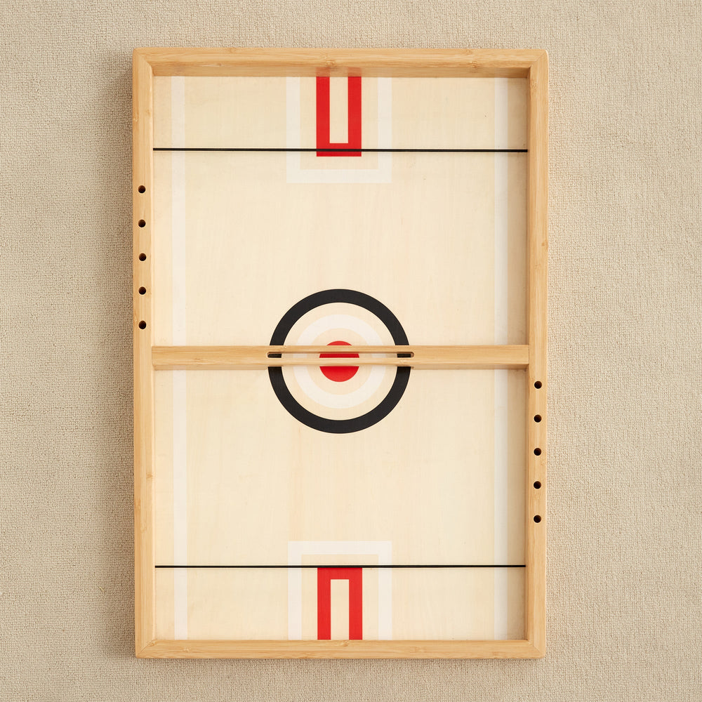 Wooden tabletop hockey game with target design on beige textured background.