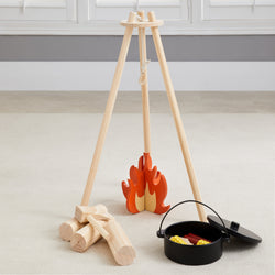 Toy wooden campfire set with logs, pot, and food for imaginative children's play.