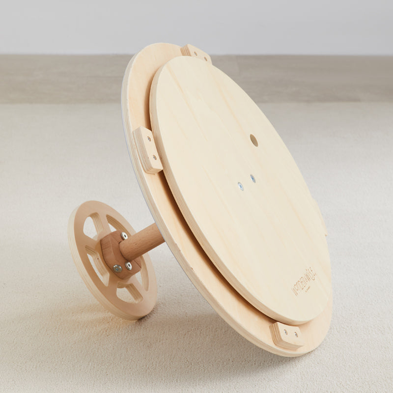 Wooden spinning wheel laying on carpet floor for textile crafting.