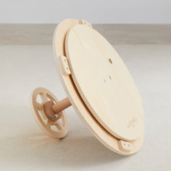 Wooden spinning wheel laying on carpet floor for textile crafting.