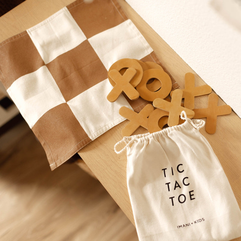 Tic Tac Toe wooden game set with grid and X and O pieces on a table.