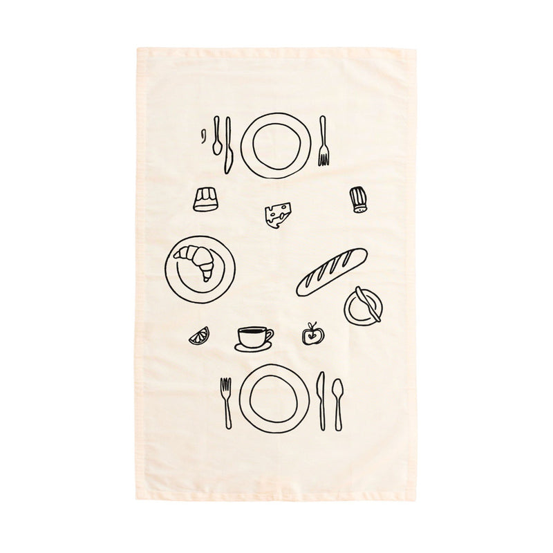 Illustrated kitchen towel with black line drawings of tableware and food items, including croissant and baguette.