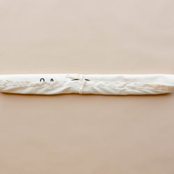 White fabric yoga mat bag with tie closure on neutral background.