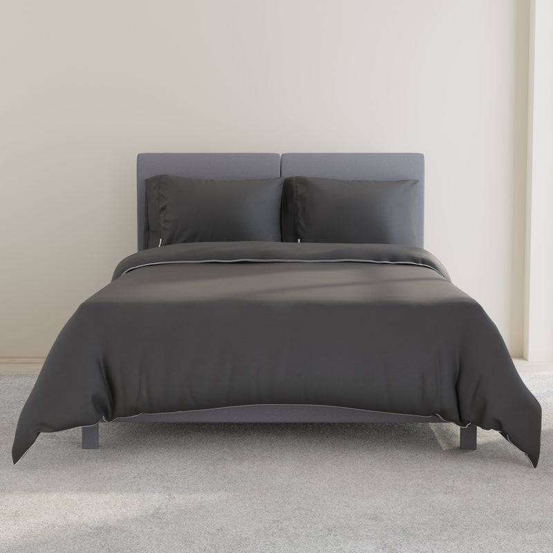 Black bedding set on modern grey bed frame in minimalist bedroom with soft carpet flooring.