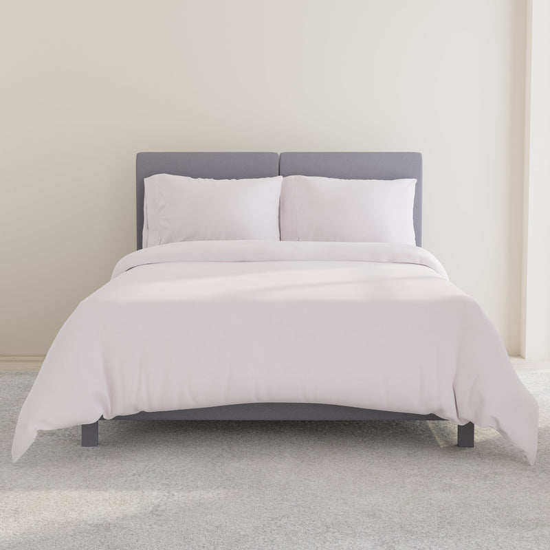 Modern bedroom with a stylish grey upholstered bed and white bedding set.