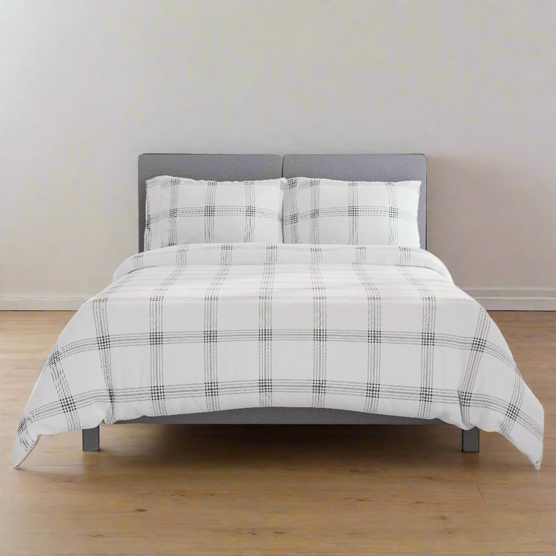 Modern grey upholstered bed with stylish checkered bedding in minimalist bedroom setting.