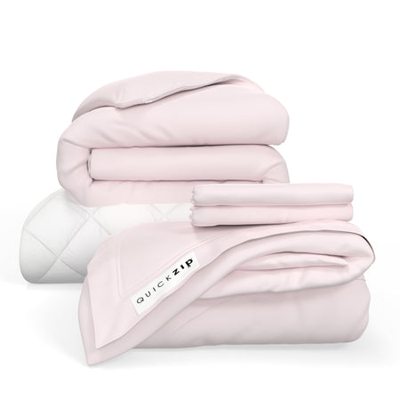 Folded pink bedding set with QuickZip label, including blankets and sheets.