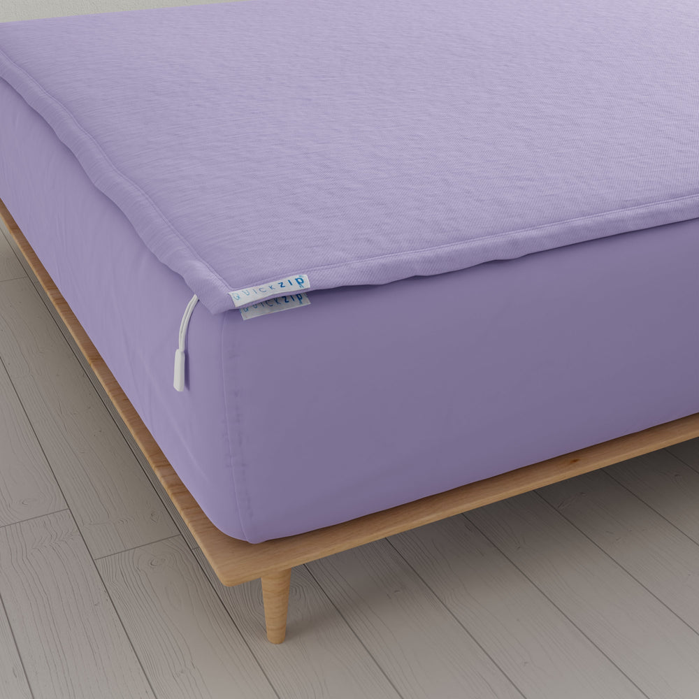 Purple zippered fitted sheet on wooden bed frame for mattress protection.