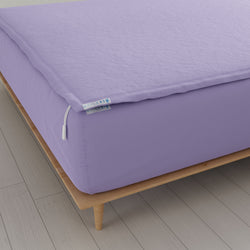 Purple zippered fitted sheet on wooden bed frame for mattress protection.