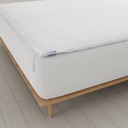 White zippered mattress cover on a modern wooden bed frame.