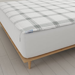Plaid pattern mattress protector on modern wooden bed frame, enhancing bedroom decor and protection.