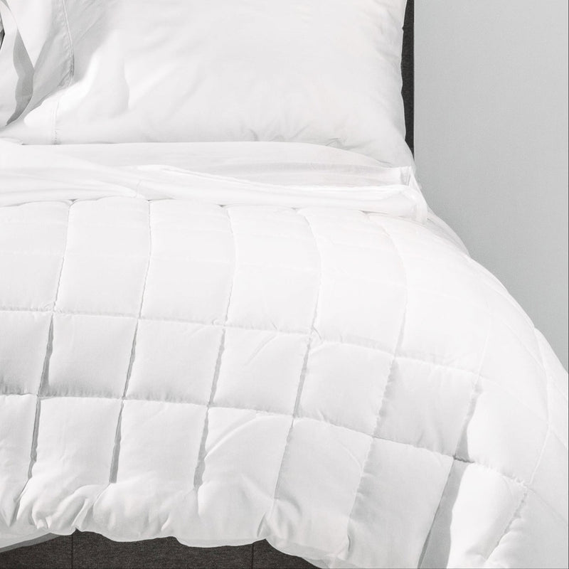Luxury white comforter set with pillows on a neatly made bed.