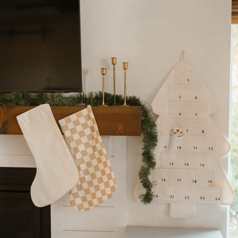 Christmas mantel decor with stockings, an advent calendar, and greenery for holiday home decoration ideas.