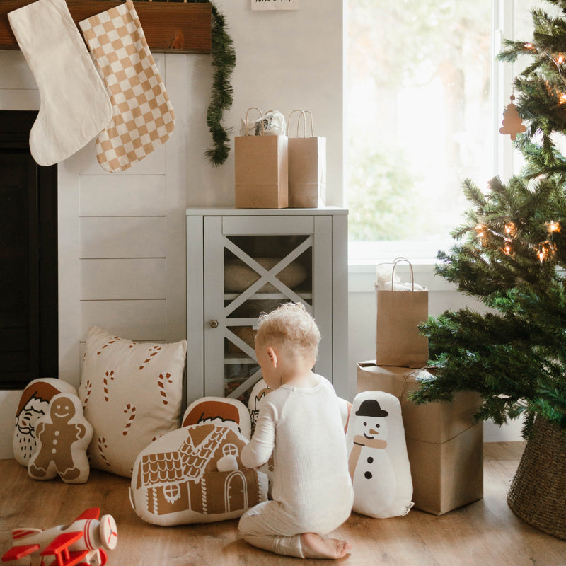 Child playing with Christmas decorations near a festive tree in cozy living room.
