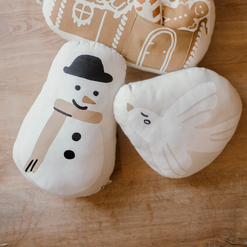 Cushions with snowman and bird designs on wooden surface.