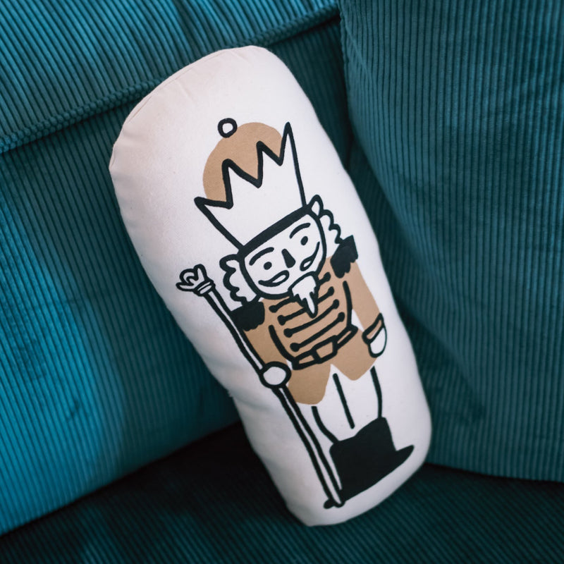 Decorative pillow with nutcracker print on teal couch.